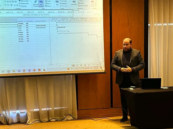 A presenter walking through a project plan on a projector screen